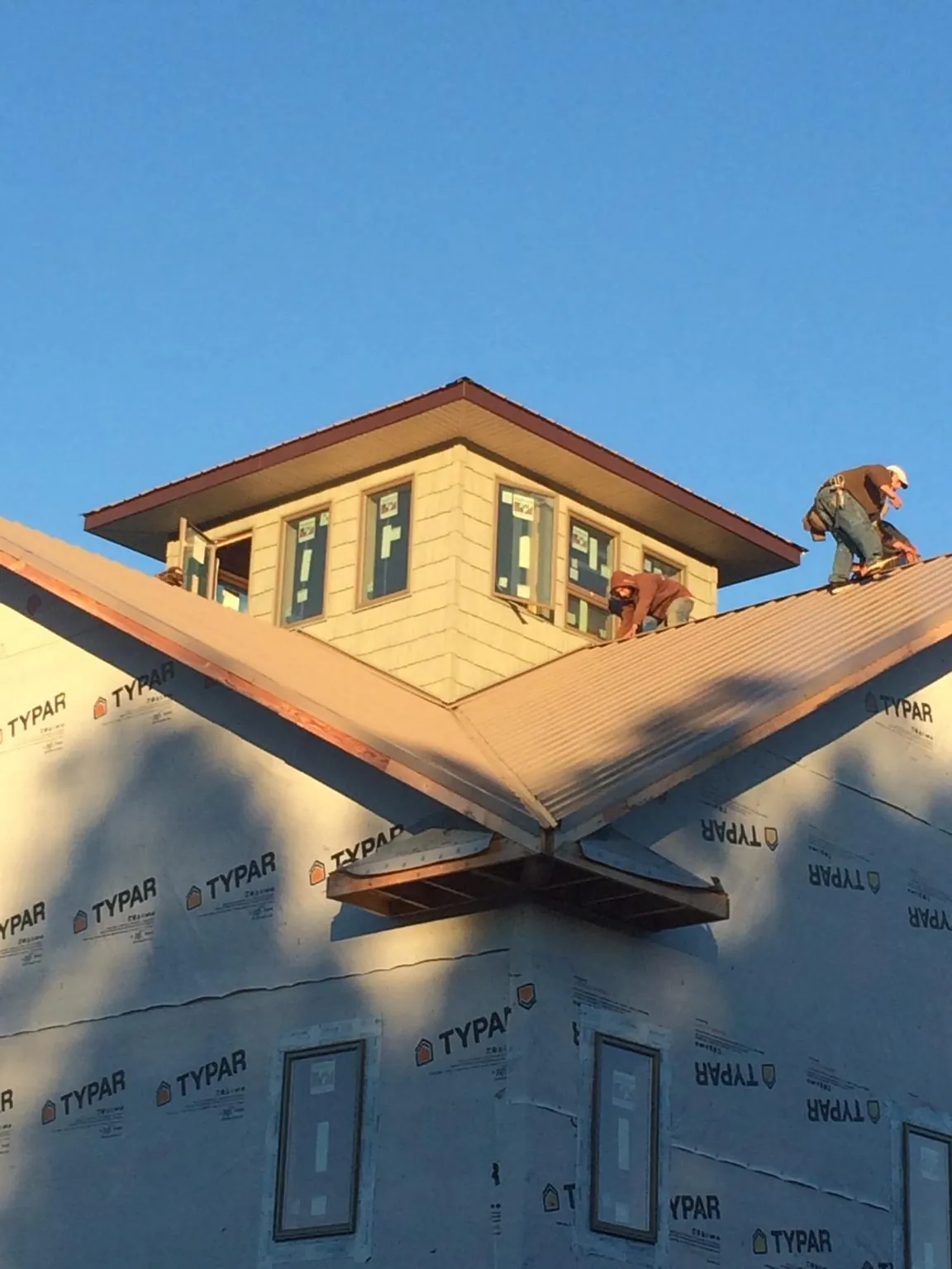 Roofers working around a rooftop cupola on a new metal roof at sunset — Roof Waterproofing in Cayuga by Roofing Brothers